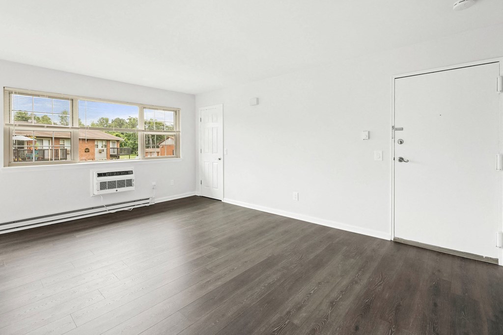 an empty living room with wood floors and a window