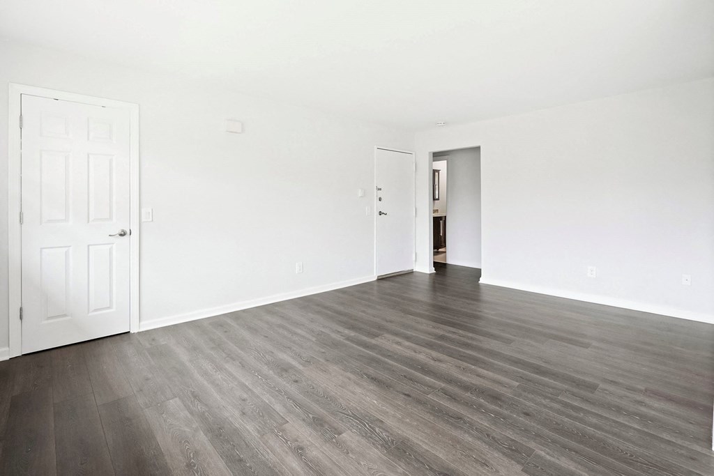 an empty living room with white walls and wood floors