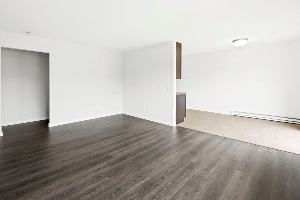 an empty living room with wood floors and white walls