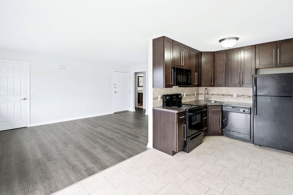 an empty kitchen with stainless steel appliances and wooden cabinets