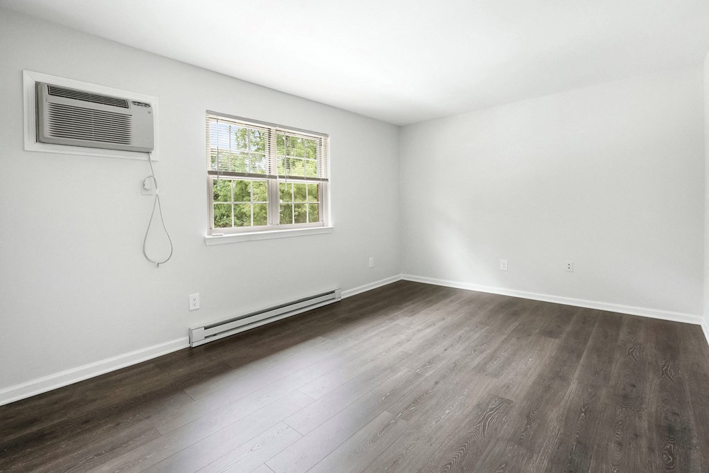an empty room with white walls and wood floors and a window