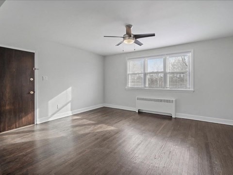 A room with a ceiling fan and a window with blinds.