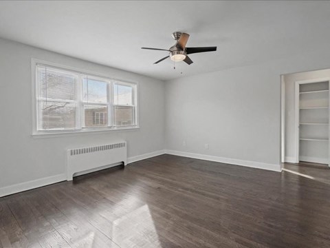 A room with a ceiling fan and a window with blinds.