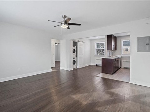 A spacious room with a ceiling fan and hardwood floors.