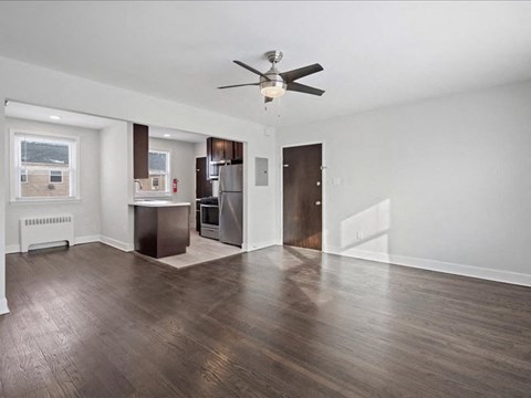 A spacious room with a ceiling fan and wooden flooring.