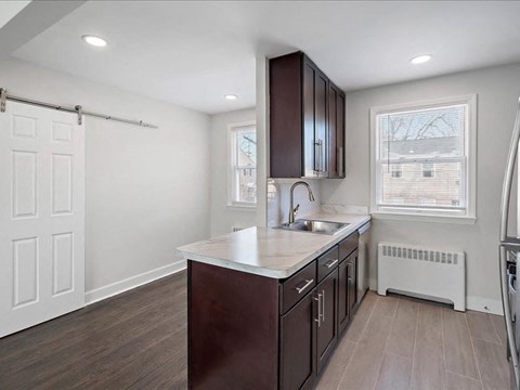 A kitchen with dark brown cabinets and a white countertop.