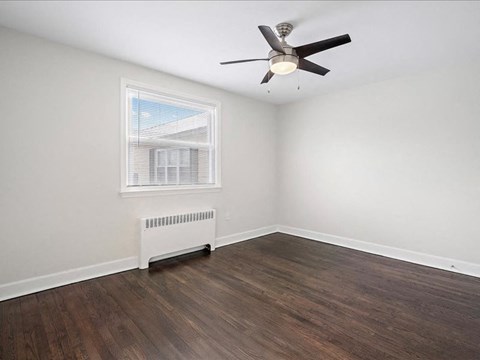 A room with a ceiling fan and a window with blinds.