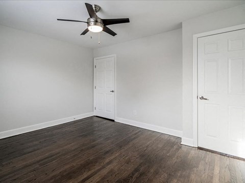 A room with a ceiling fan and two doors.