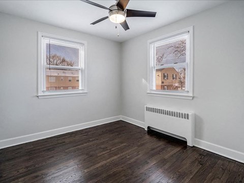 A room with a ceiling fan and a window overlooking a building.