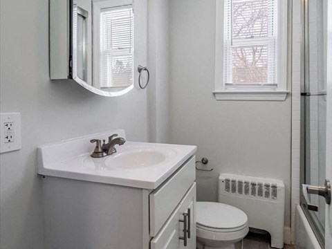 A white bathroom with a toilet, sink, and window.