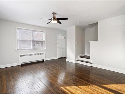 A room with a ceiling fan and wooden floors.