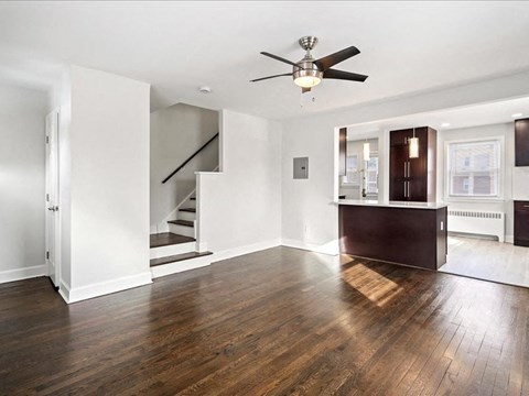 A room with a ceiling fan and wooden floors.