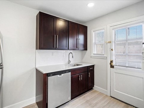 A kitchen with dark brown cabinets and white countertops.