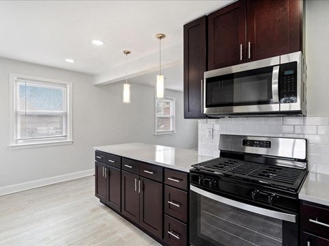 A modern kitchen with dark wood cabinets and stainless steel appliances.