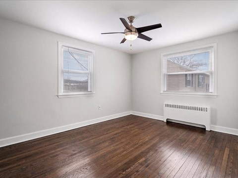 A room with a ceiling fan and a wood floor.