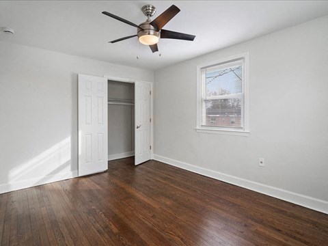 A room with a ceiling fan and a window with blinds.