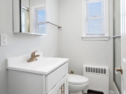 A white bathroom with a toilet, sink, and mirror.