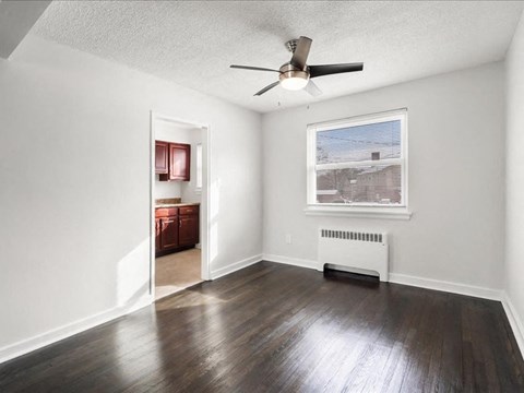 A room with a ceiling fan and a window with a view of a building outside.