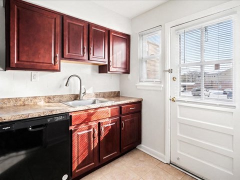 A kitchen with brown cabinets and a black dishwasher.