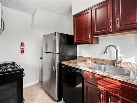 A kitchen with a stove, refrigerator, and sink.