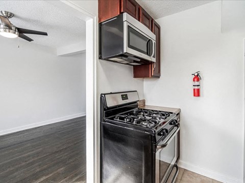 A black stove in a kitchen with a white wall and a fan.