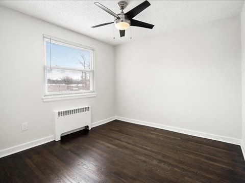 A room with a ceiling fan and a window with blinds.