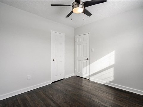 A room with a ceiling fan and two doors.