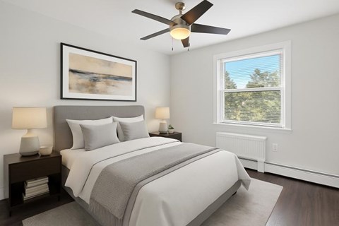A bedroom with a large bed, a ceiling fan, and a painting on the wall.