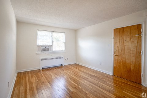 an empty living room with wood floors and a wooden door