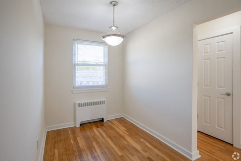 an empty living room with a wood floor and white walls