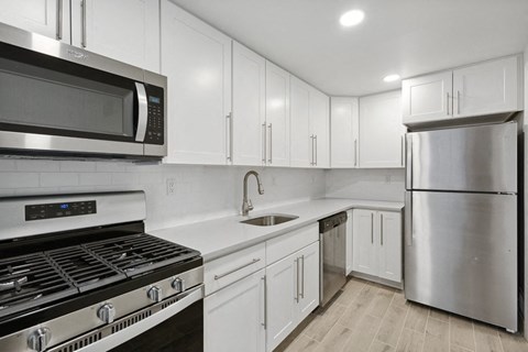 a white kitchen with stainless steel appliances and white cabinets