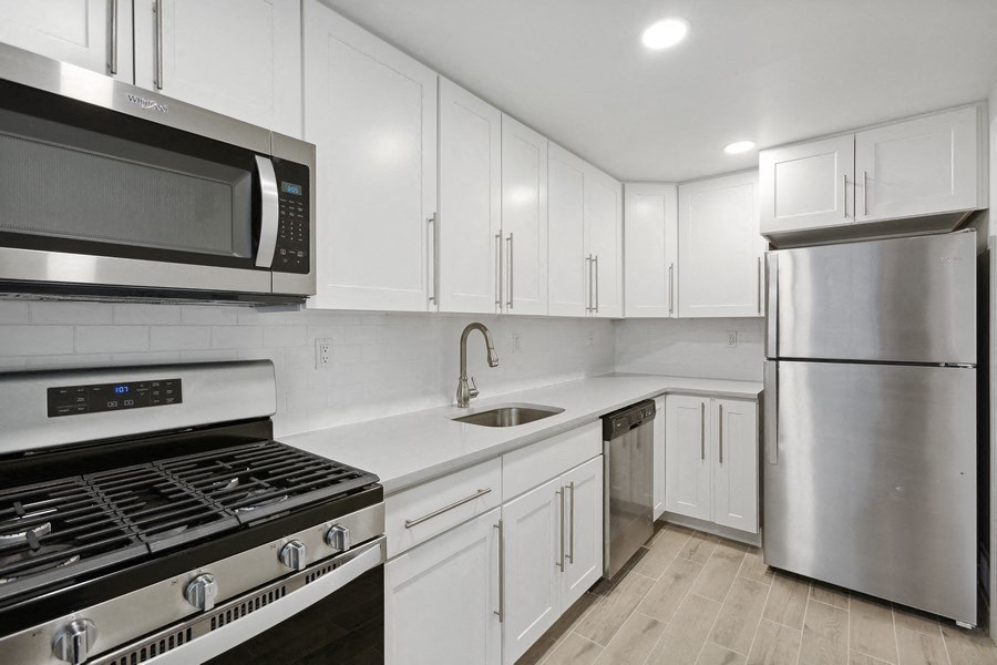 a white kitchen with stainless steel appliances and white cabinets