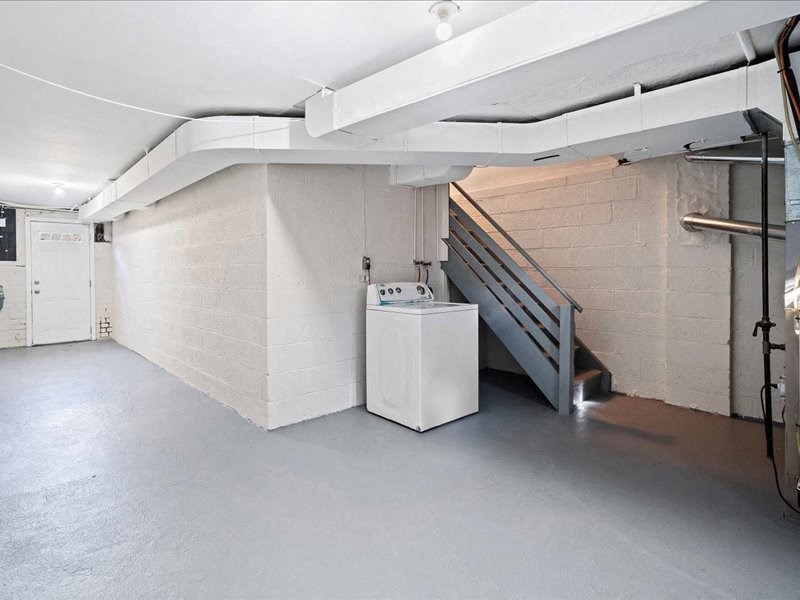 the basement of a building with a staircase and a refrigerator