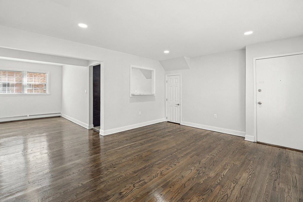 an empty living room with white walls and wood floors