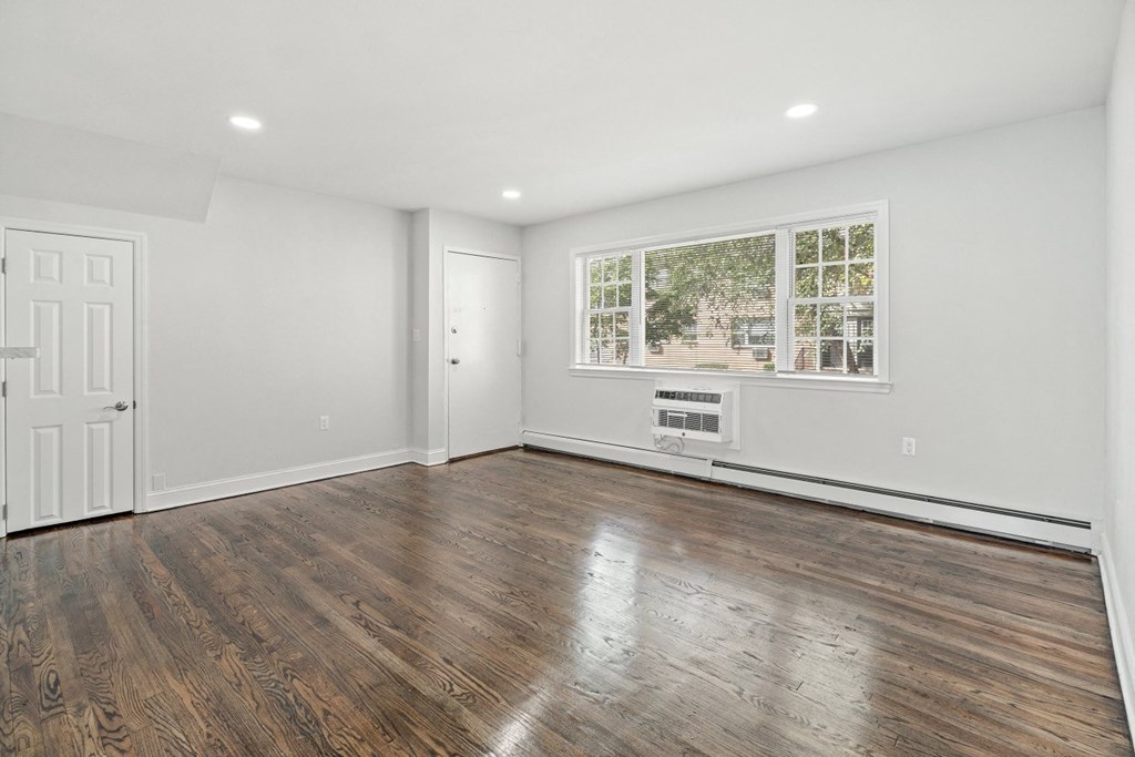 a living room with white walls and wooden floors and a window