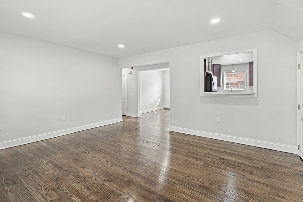 a renovated living room with white walls and wood flooring