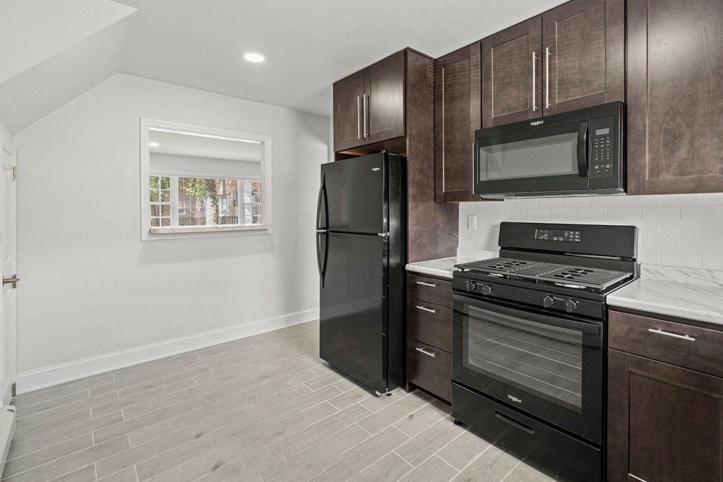 a kitchen with black appliances and dark wood cabinets