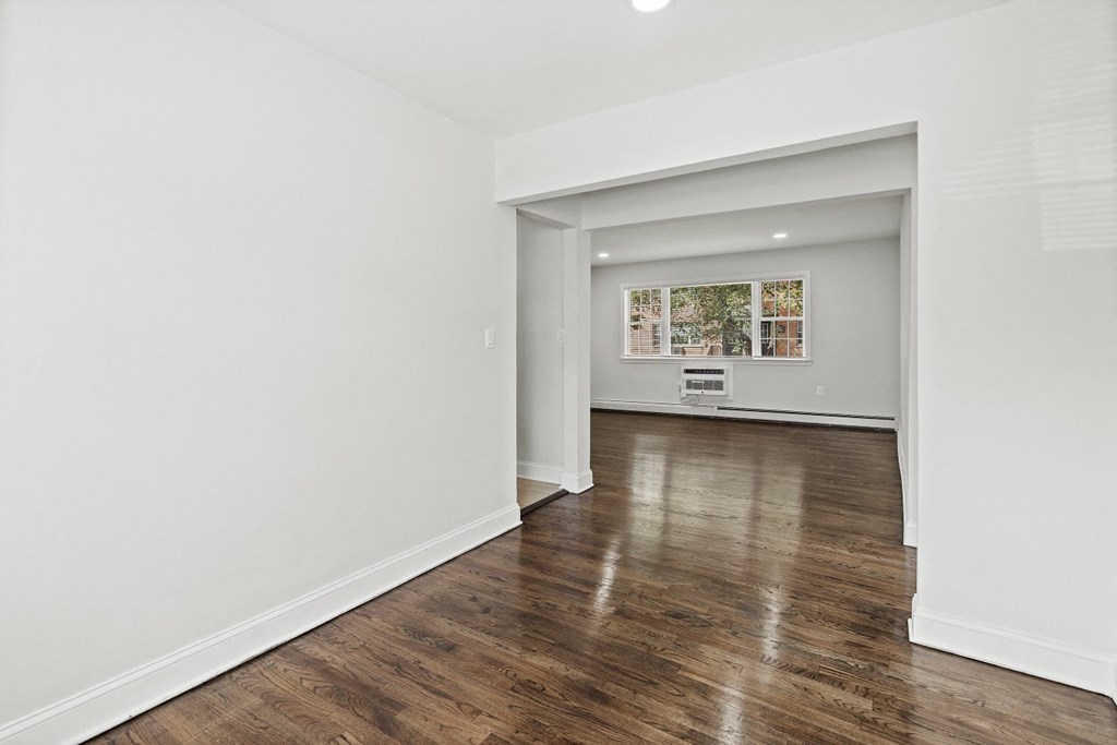 a living room and dining room with white walls and wood floors