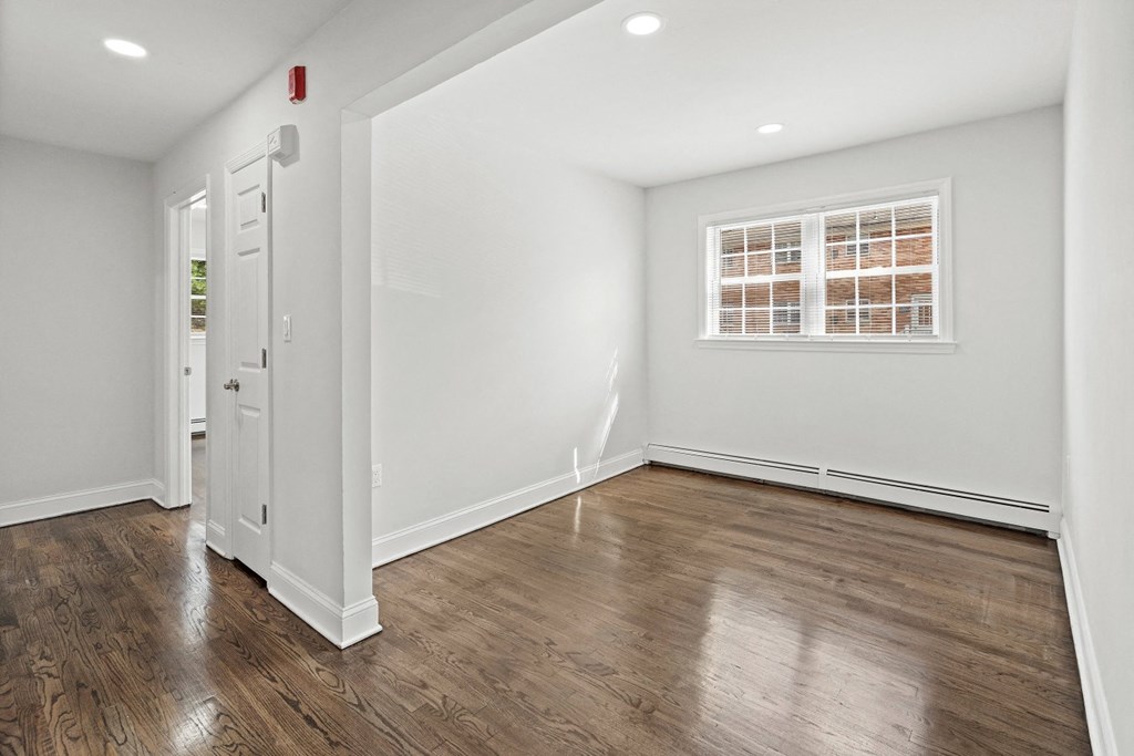 a living room with white walls and a window and wooden floors