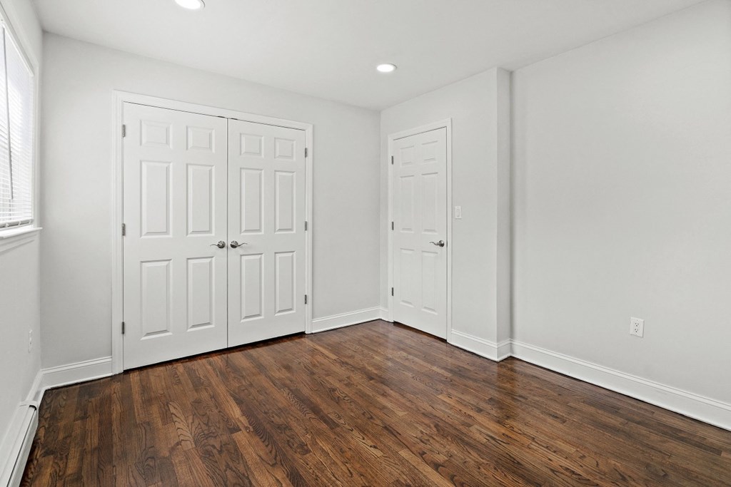 a bedroom with white walls and white doors and wood floors