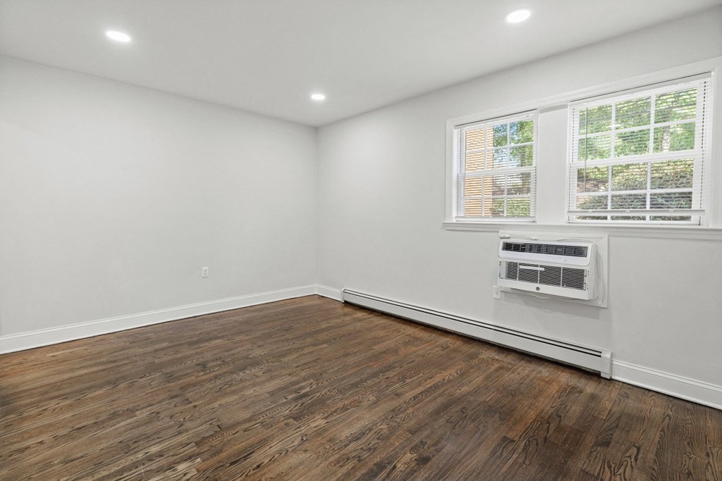 an empty living room with white walls and wood flooring and a window