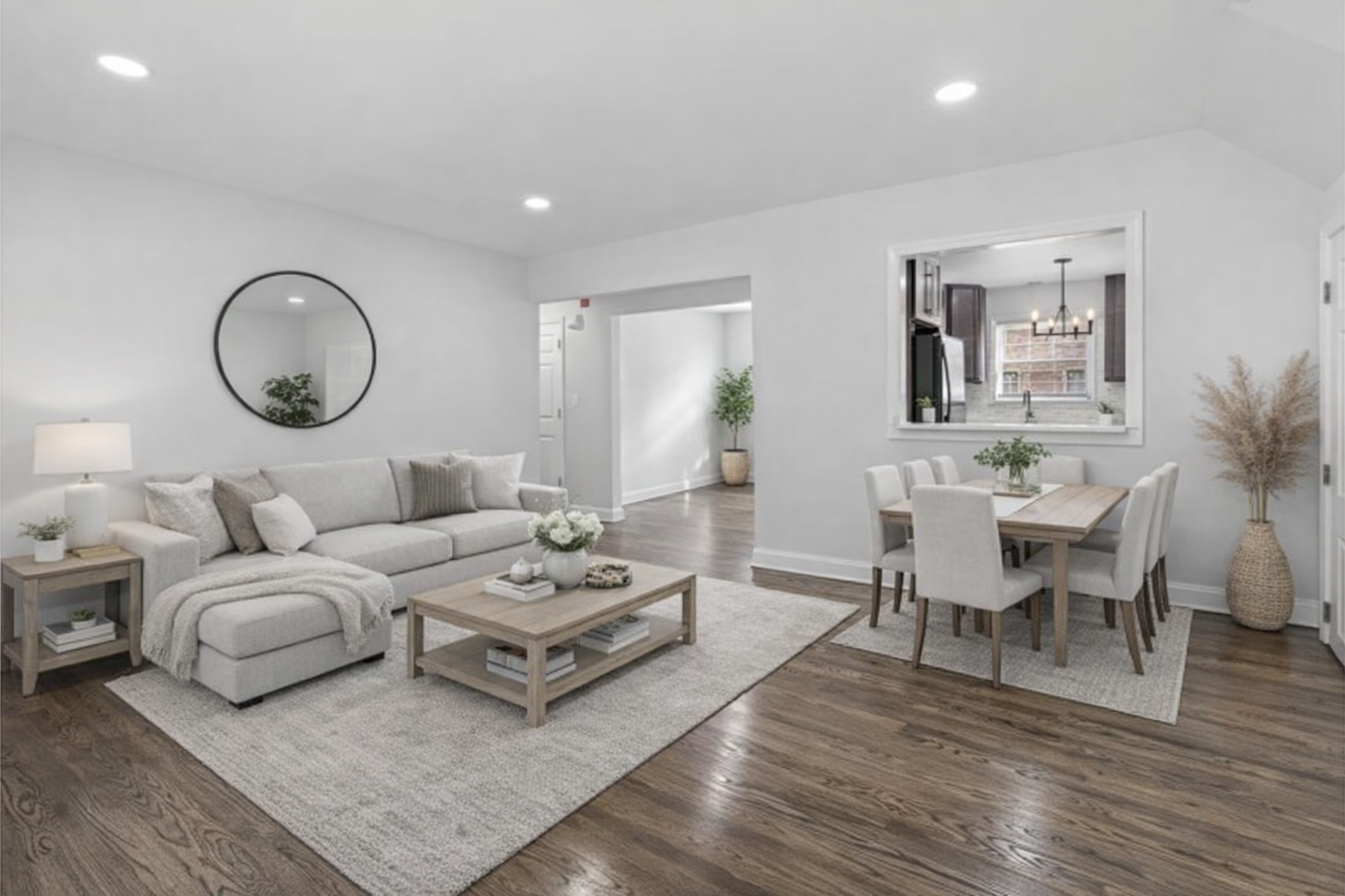 A modern living room with a grey sofa, a white dining table and chairs, and a wooden coffee table.