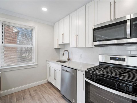 A kitchen with white cabinets and a black stove top oven.