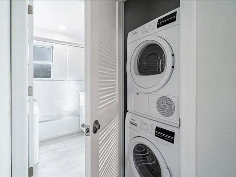 A white front-loading washing machine is in a laundry room.