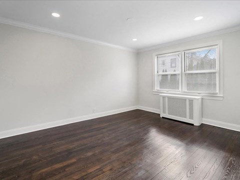 A room with wooden floors and a window with blinds.