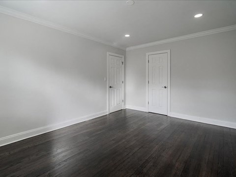 A room with two white doors and wooden floors.