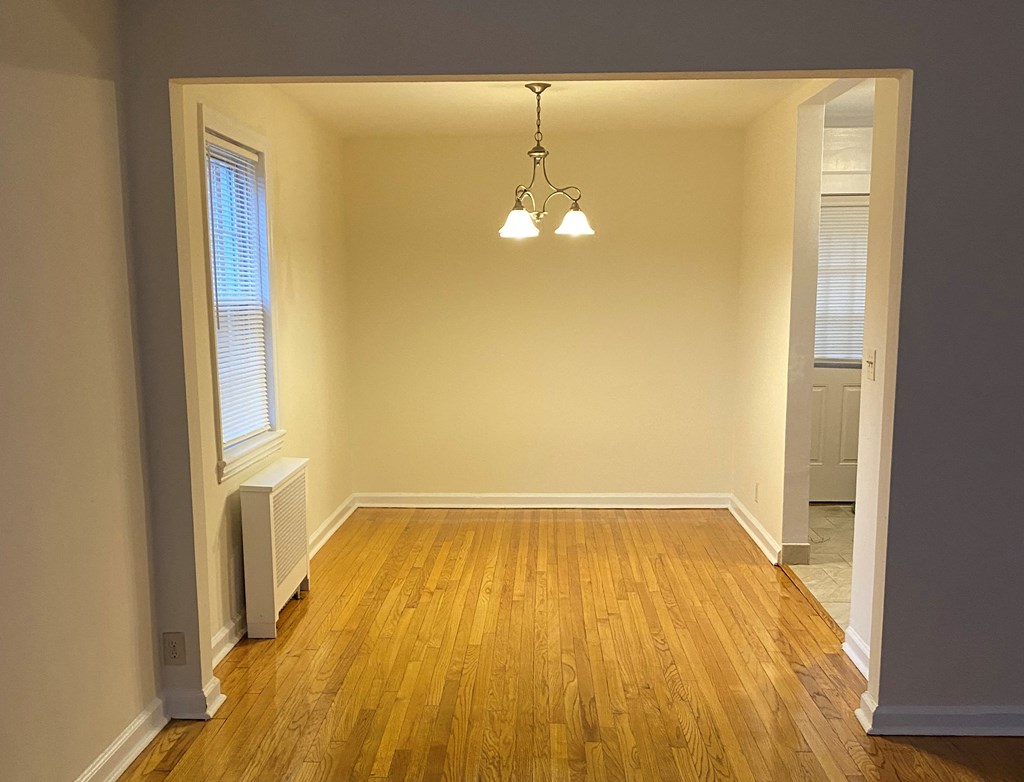 an empty living room with wood floors and a chandelier