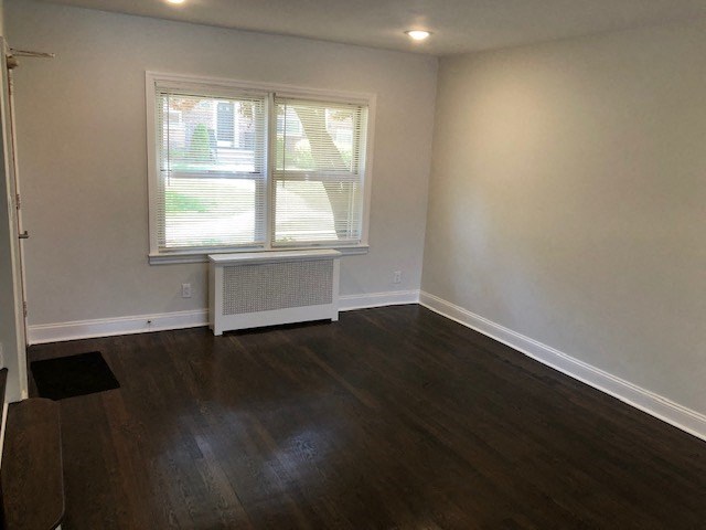 an empty room with a window and wooden floors