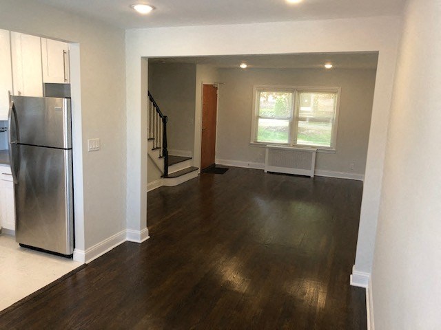 an empty living room with a stainless steel refrigerator