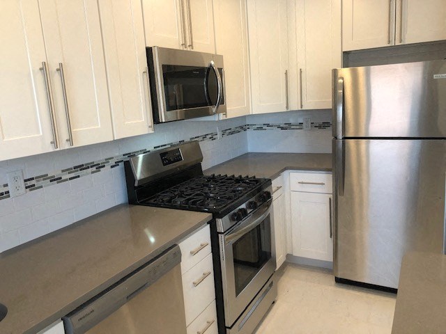a kitchen with stainless steel appliances and white cabinets